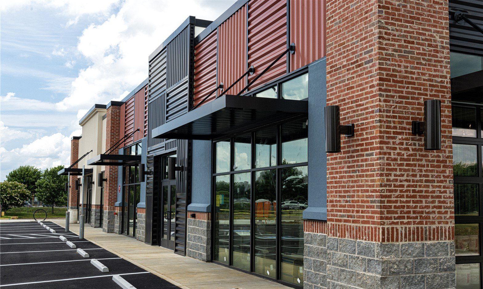 Commercial storefront with brick and metal facade, awnings, and large glass windows.