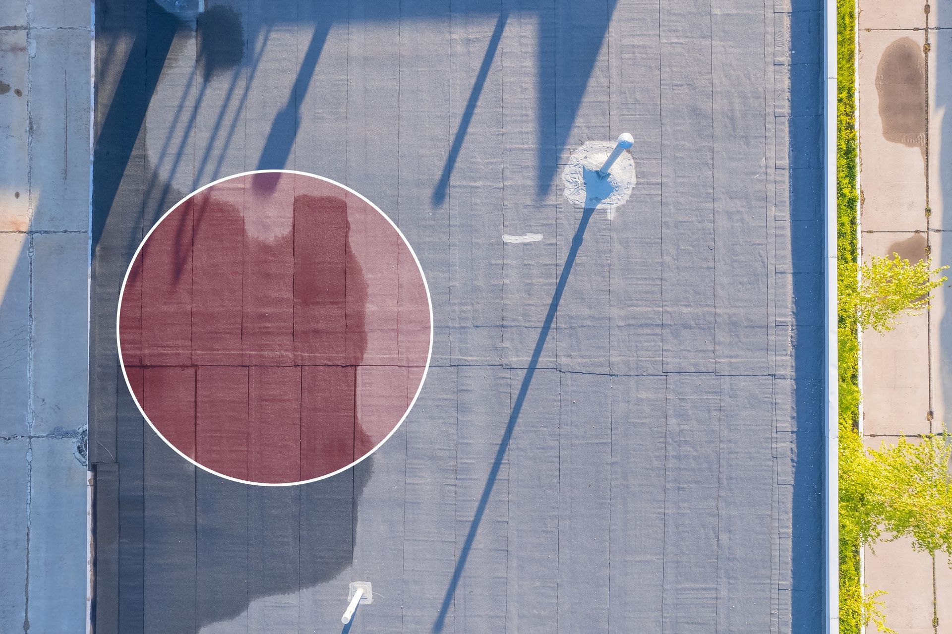 Overhead view of a basketball court with a red painted area inside the white circle, and shadow of pole.