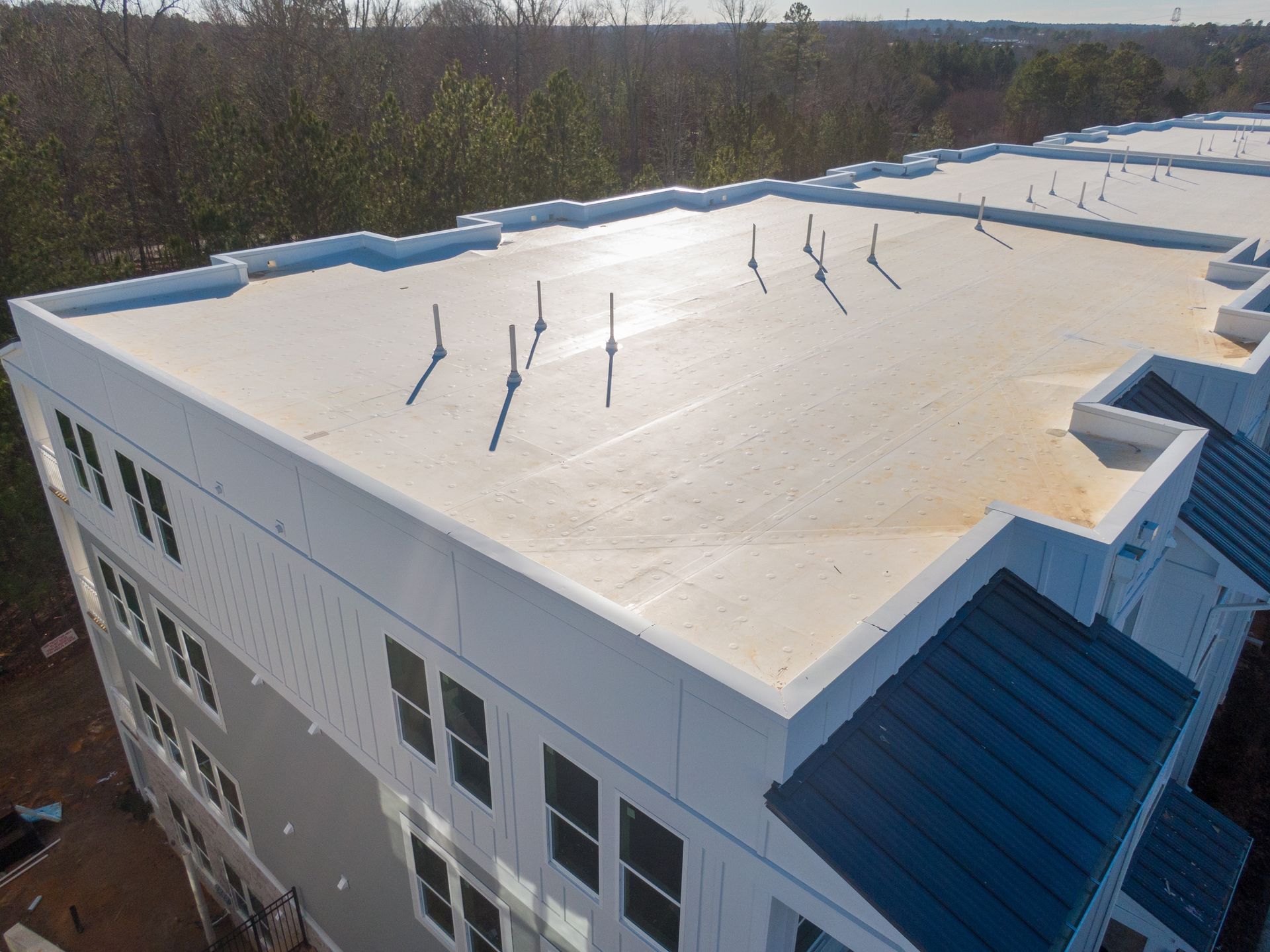 Aerial view of a flat white roof with vent pipes on a modern building.
