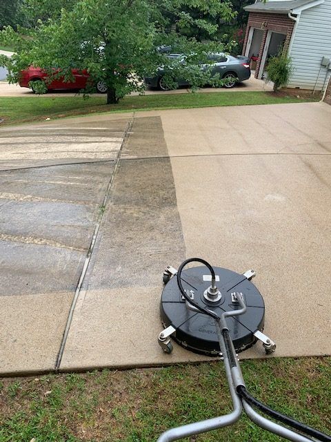 A surface cleaner on a driveway, showing a clear contrast between dirty concrete and a recently cleaned, lighter section.