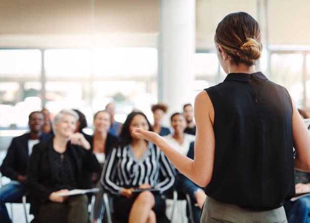 A woman is giving a presentation to a group of people sitting in chairs.