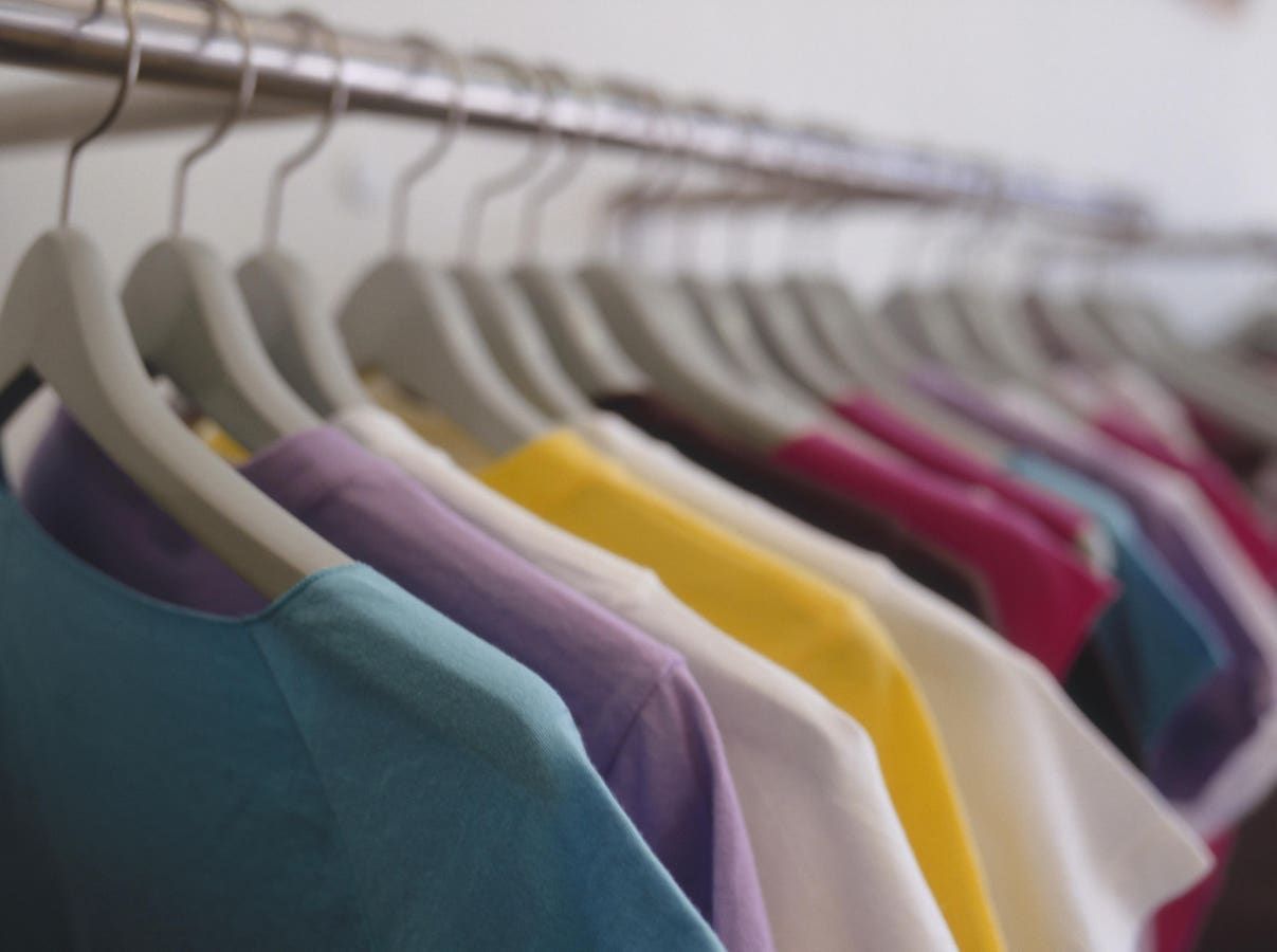A row of colorful shirts are hanging on a rack