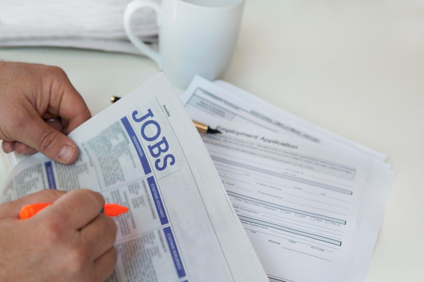 A person is looking for a job in a newspaper.