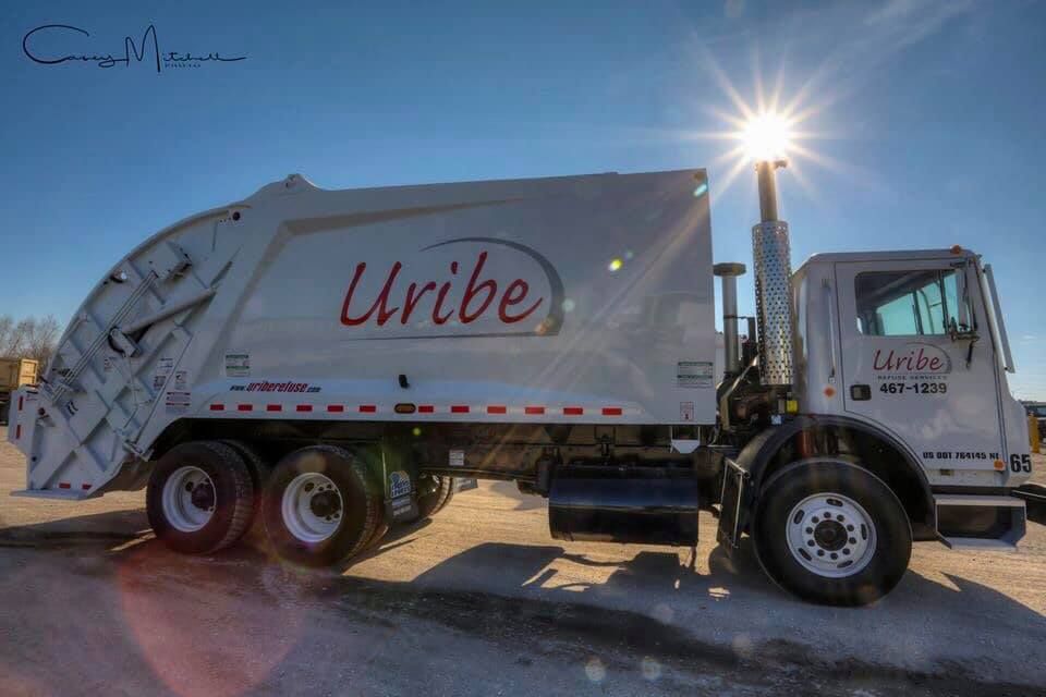 A white garbage truck with the word uribe on it