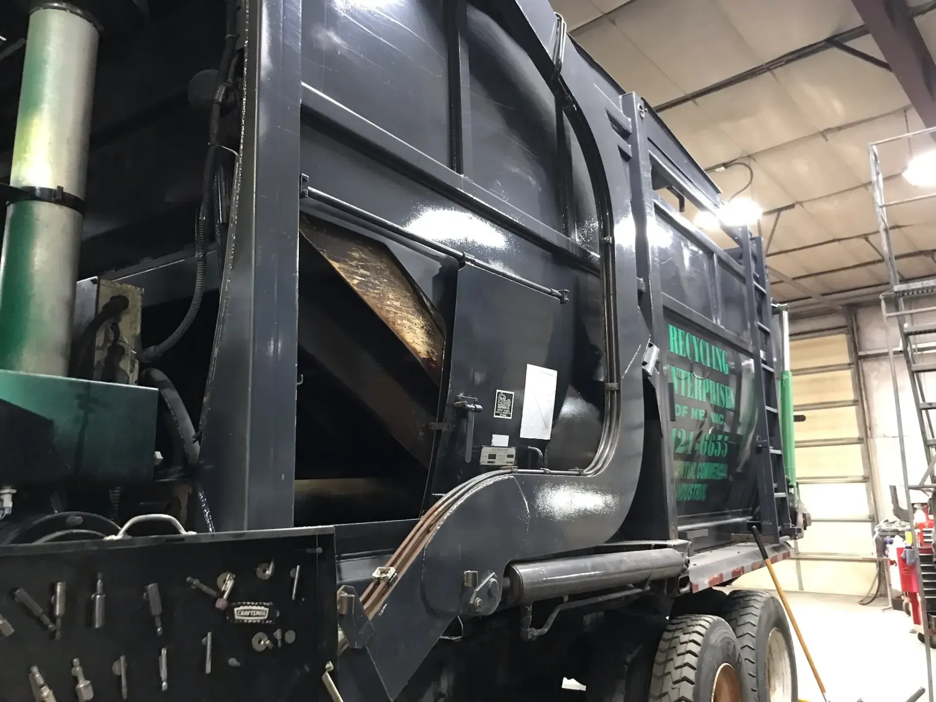 A garbage truck is parked in a garage.
