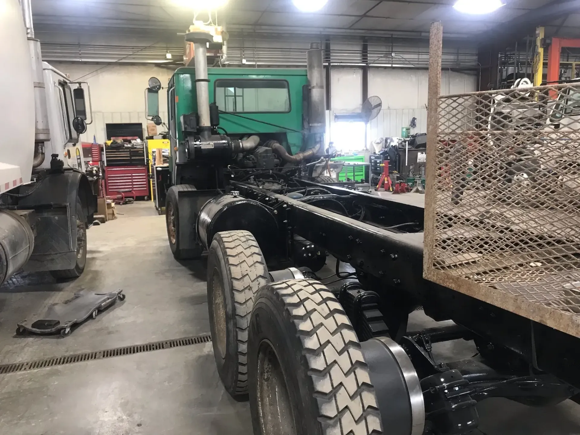 A green truck is being built in a garage.