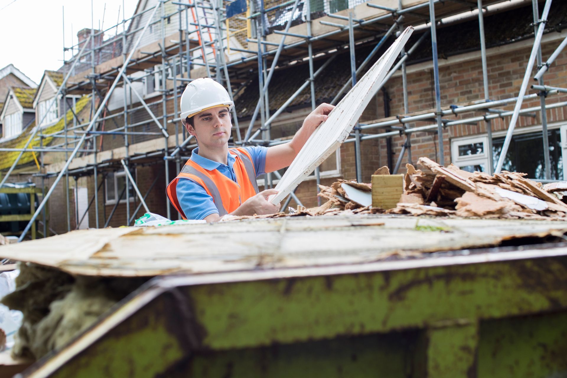 A construction worker is holding a piece of wood at a construction site.