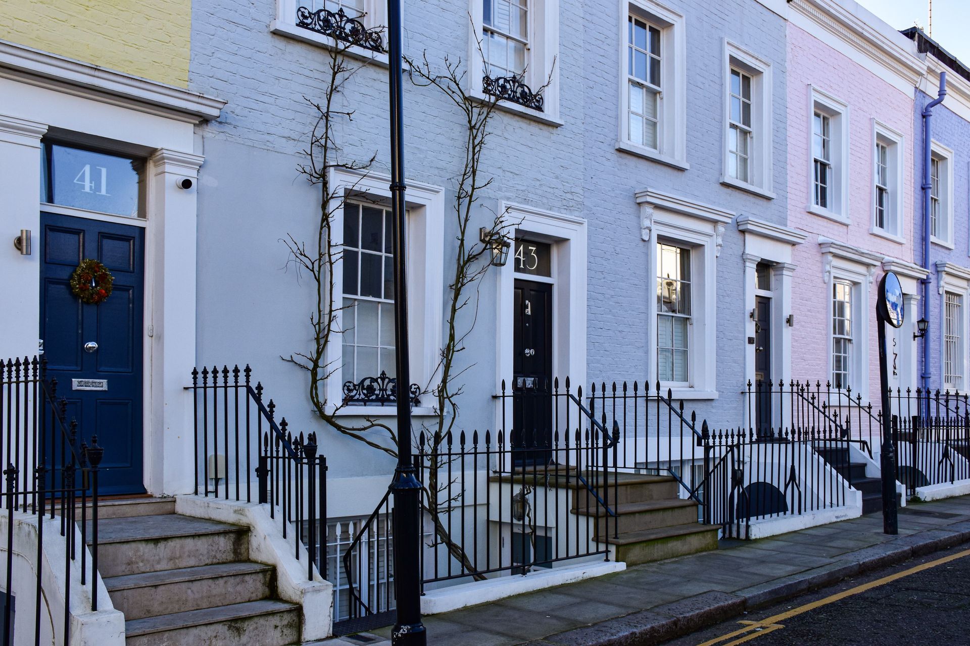 Row of pastel terraced houses with blue doors and white railings on a quiet street