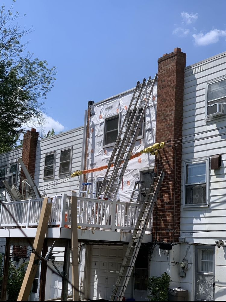 House exterior with ladders and construction materials; blue sky.