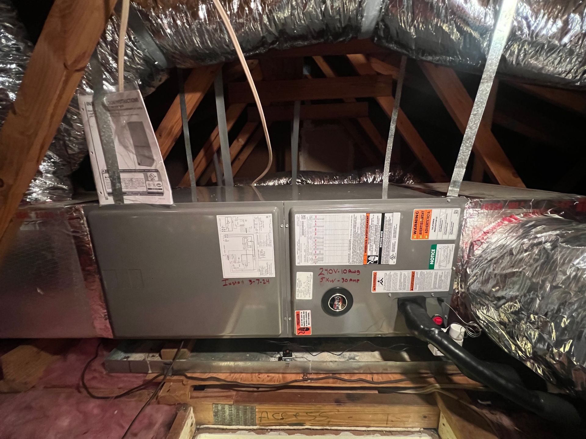 HVAC unit in an attic with insulated ductwork and wooden rafters.