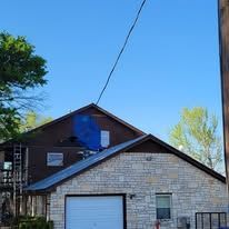 Two-story building with a light stone facade and a dark brown upper level, blue sky above.