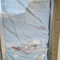 Broken window covered in white material within a metal frame.