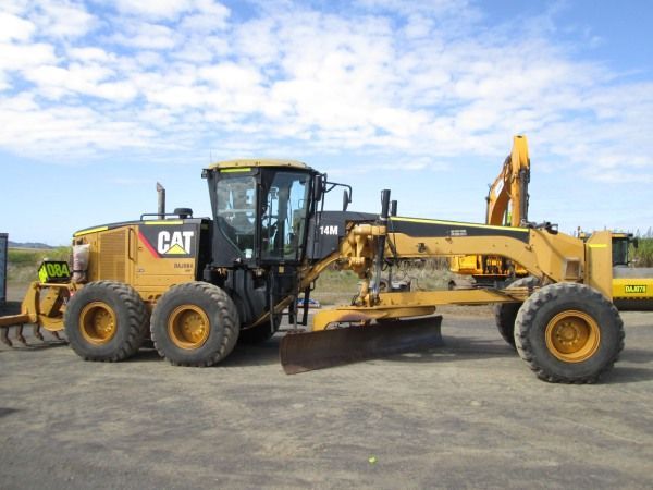 A cat tractor is parked in a dirt lot