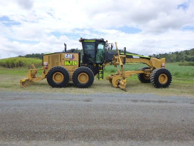 A cat tractor is parked in a dirt lot