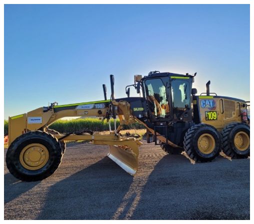 A yellow and black caterpillar grader is parked on the side of the road.