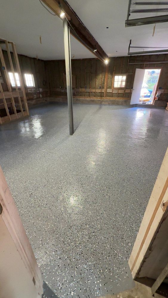 Empty unfinished room with exposed studs, concrete floor, and a bright doorway at the far end.
