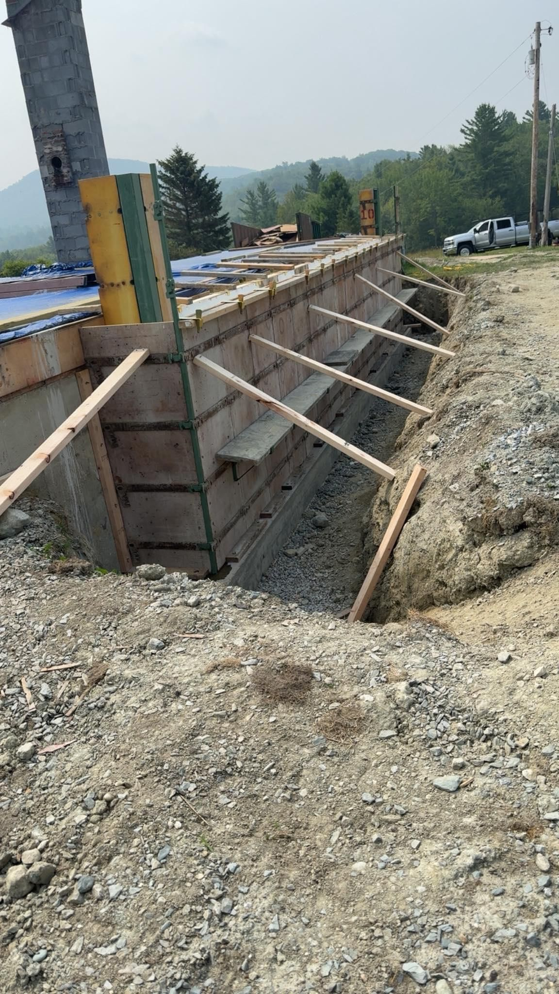 Roadside construction trench with wooden bracing and gravel beside a paved road
