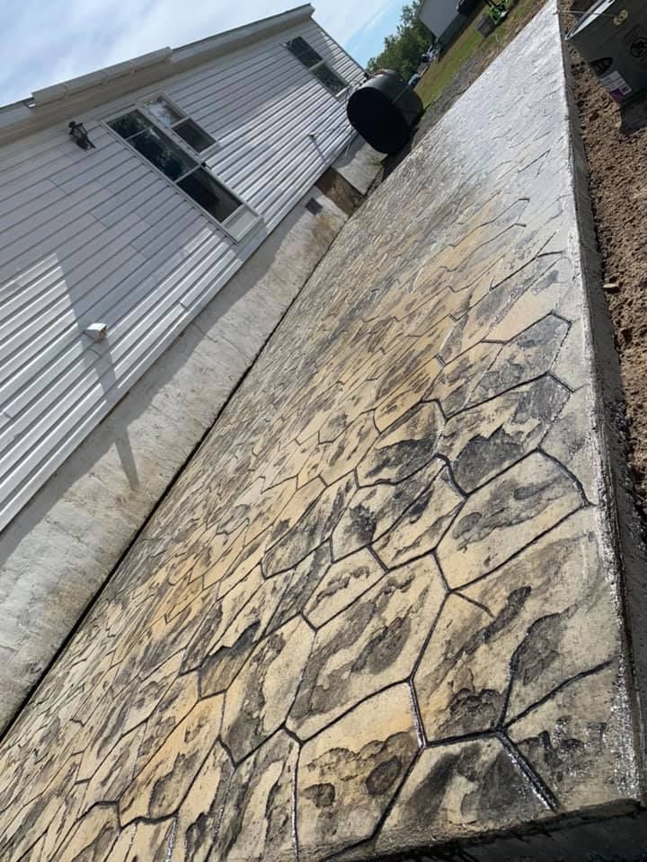 Stamped concrete walkway beside a white house, viewed at an angle under a cloudy sky.