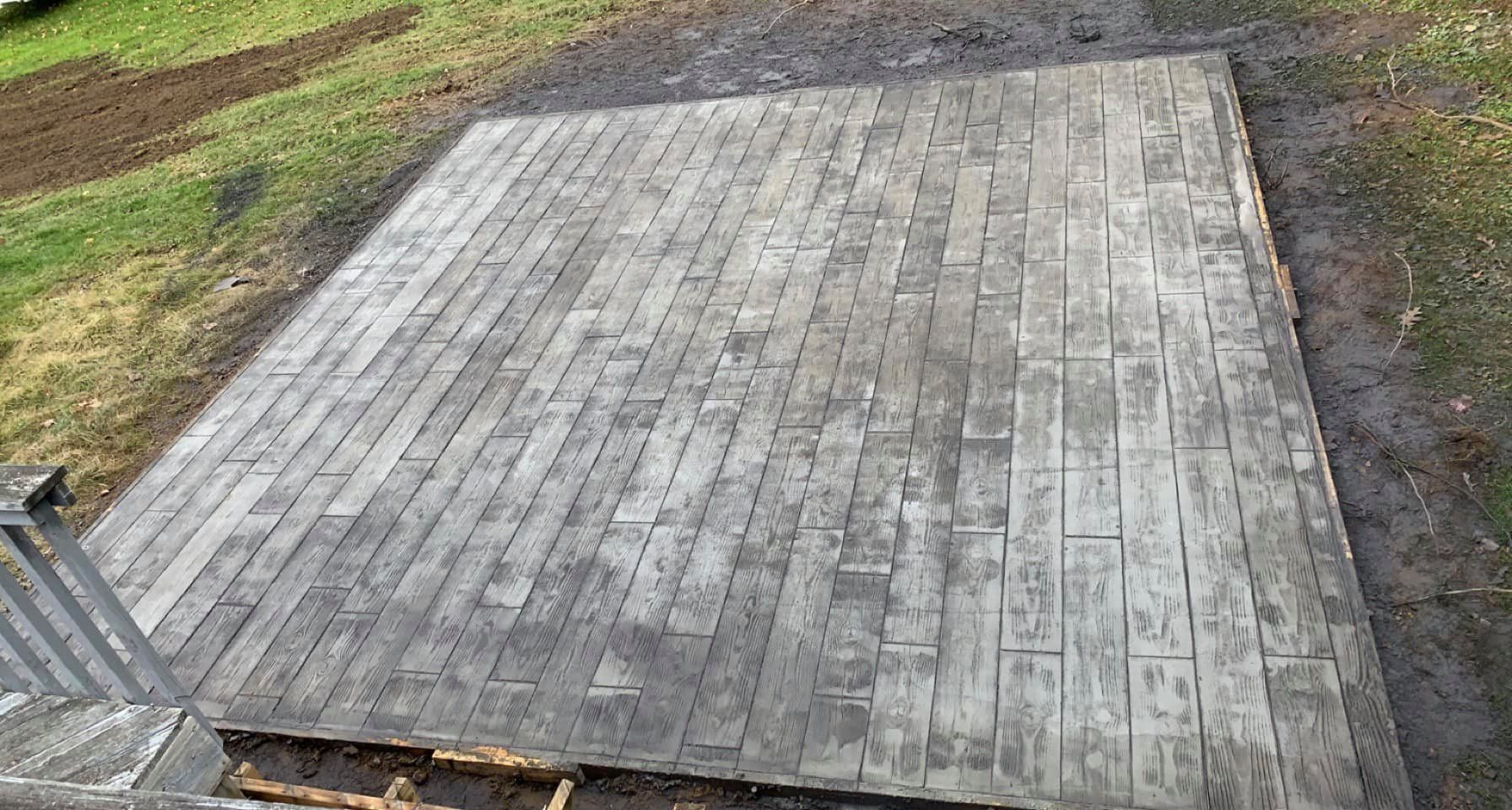 Weathered wooden deck platform beside grass and dirt, viewed from above.