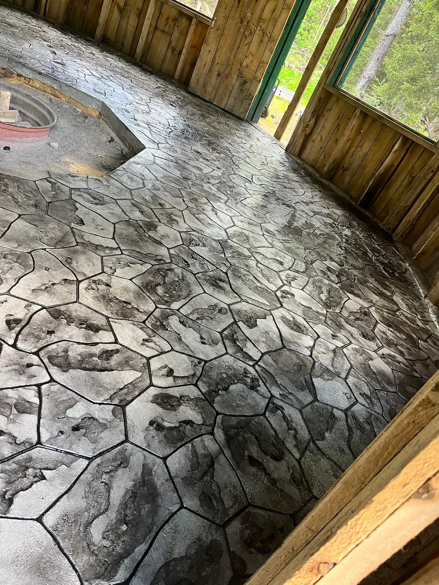 Cracked gray concrete floor in a wooden outdoor pavilion with open sides.