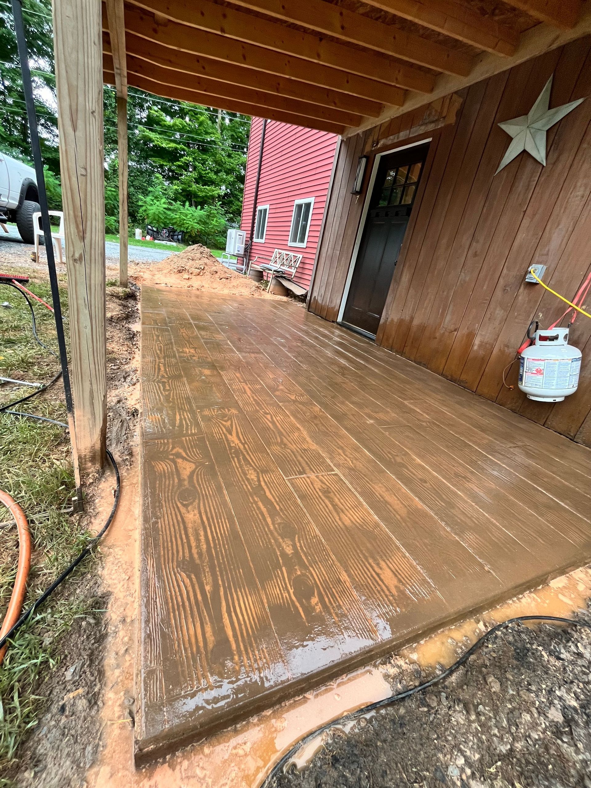 Covered wooden porch with wet planks, a white star on the wall, and a red house in the background