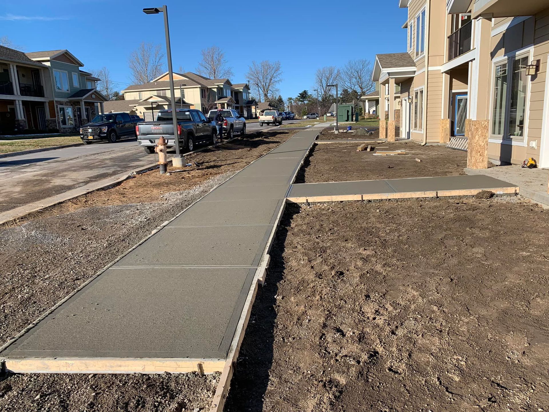 New sidewalk under construction beside row homes on a sunny day