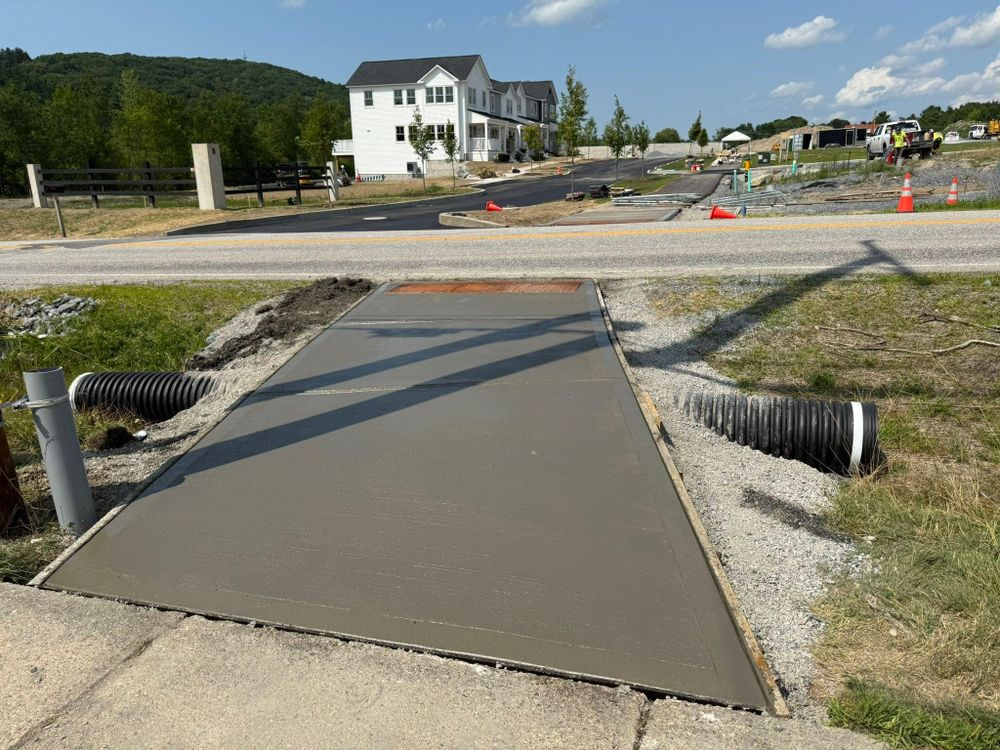New concrete sidewalk crossing a drainage trench at a residential construction site