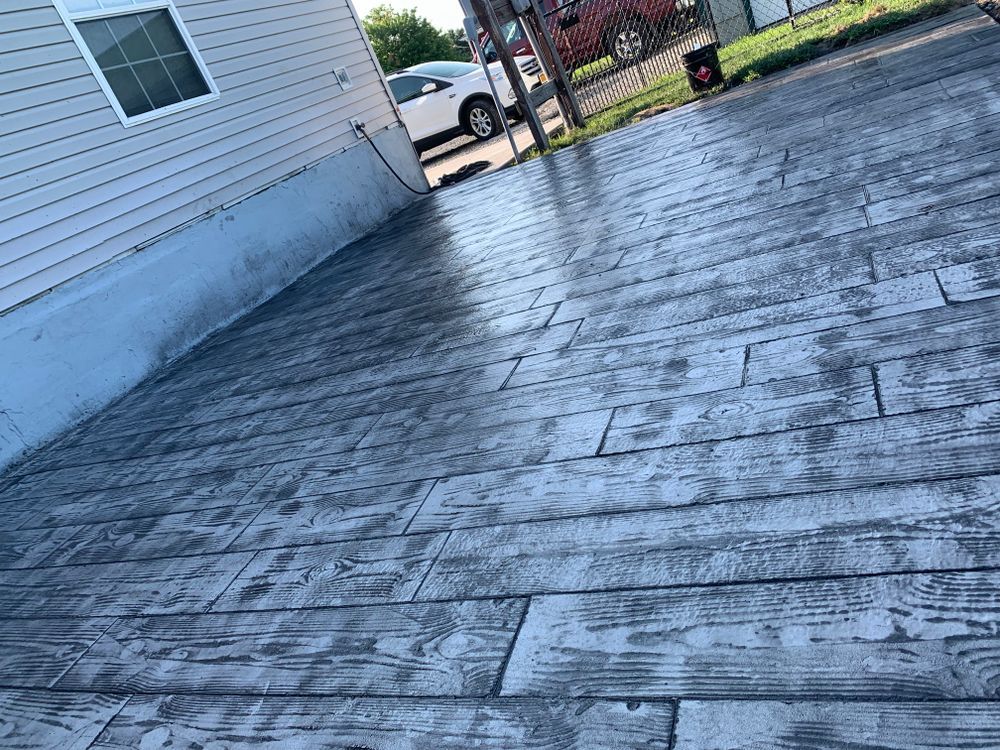 Wet wooden deck beside a white house, with a parked car and grassy yard in the background.