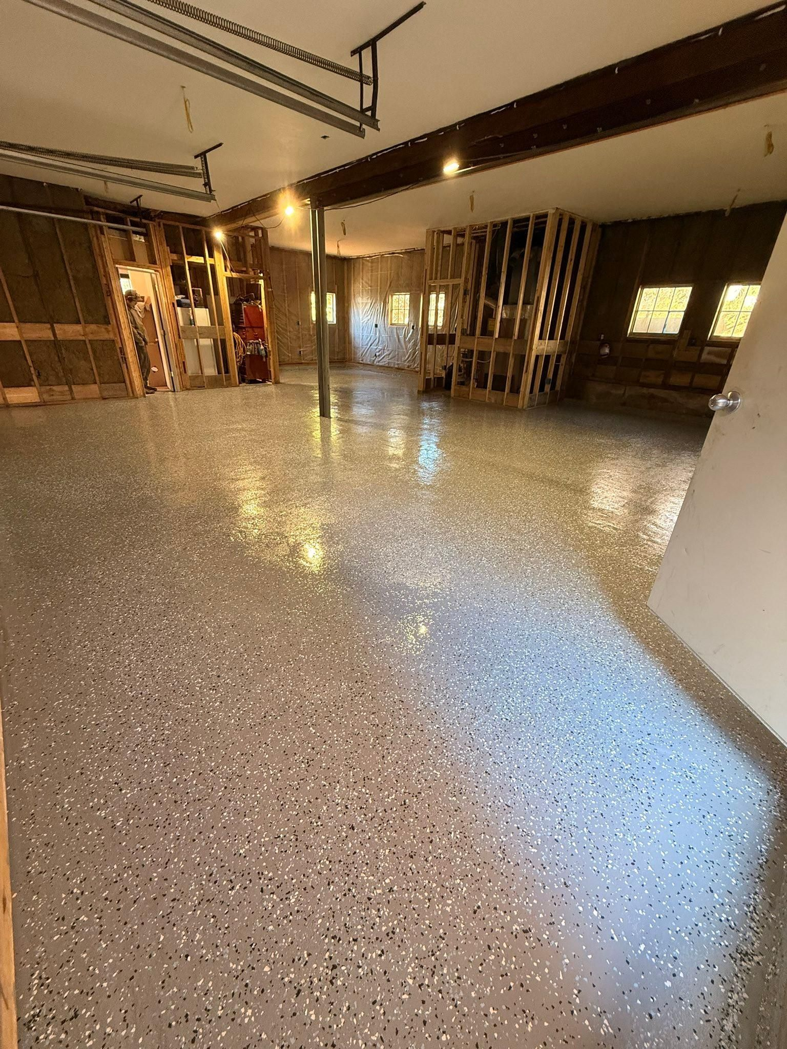 Empty modern room with speckled floor, wooden lattice walls, and ceiling lights reflecting on the polished surface