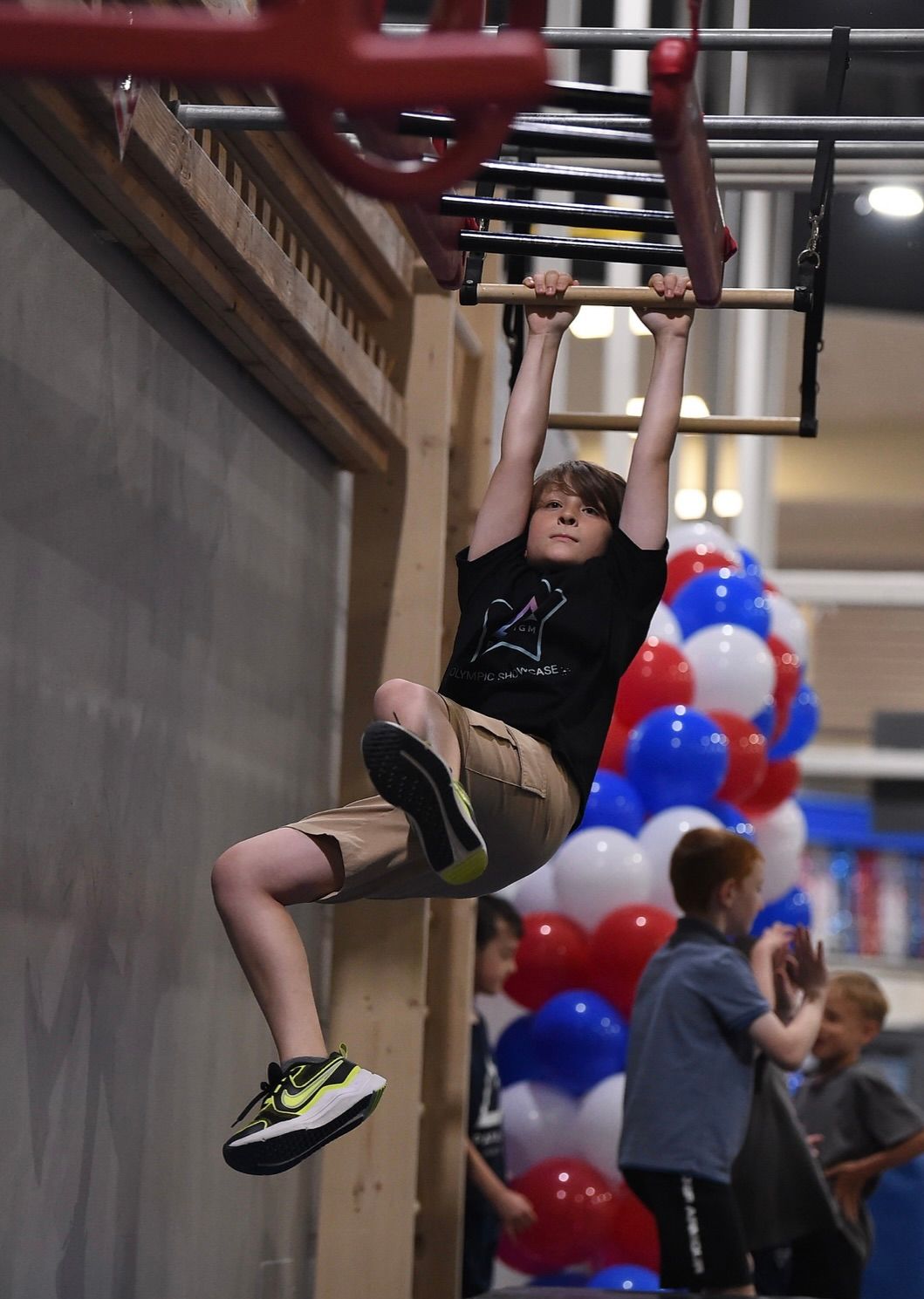 A young boy is climbing up a climbing wall.
