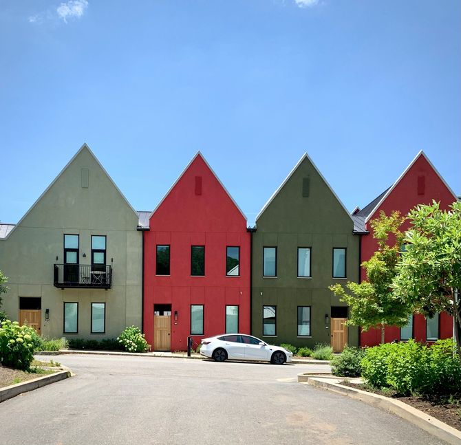 Row of colorful modern houses with a white car parked in front under a blue sky