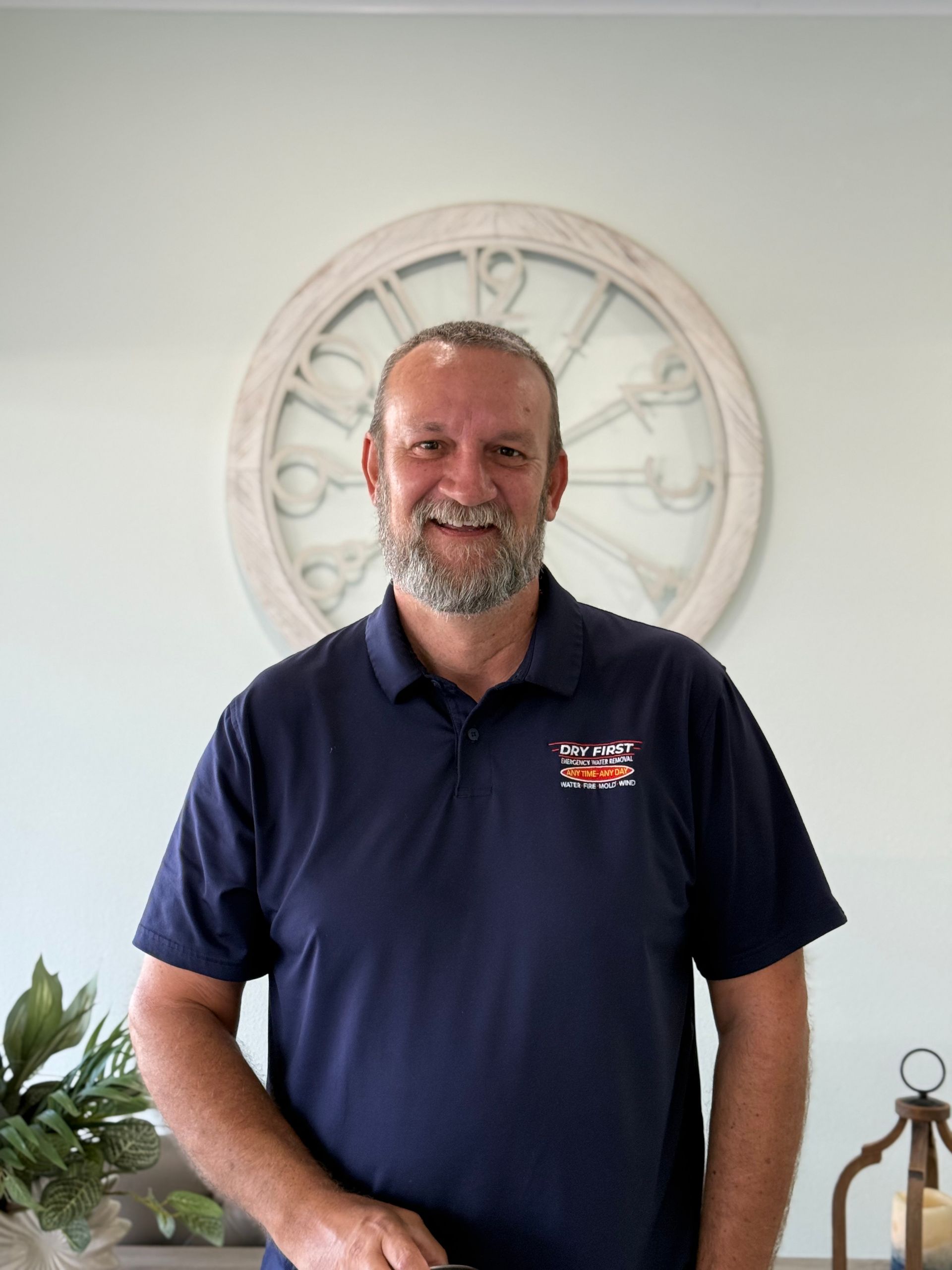 A A team member of dryfirst restoration company  with a beard and a dark blue polo shirt smiling 