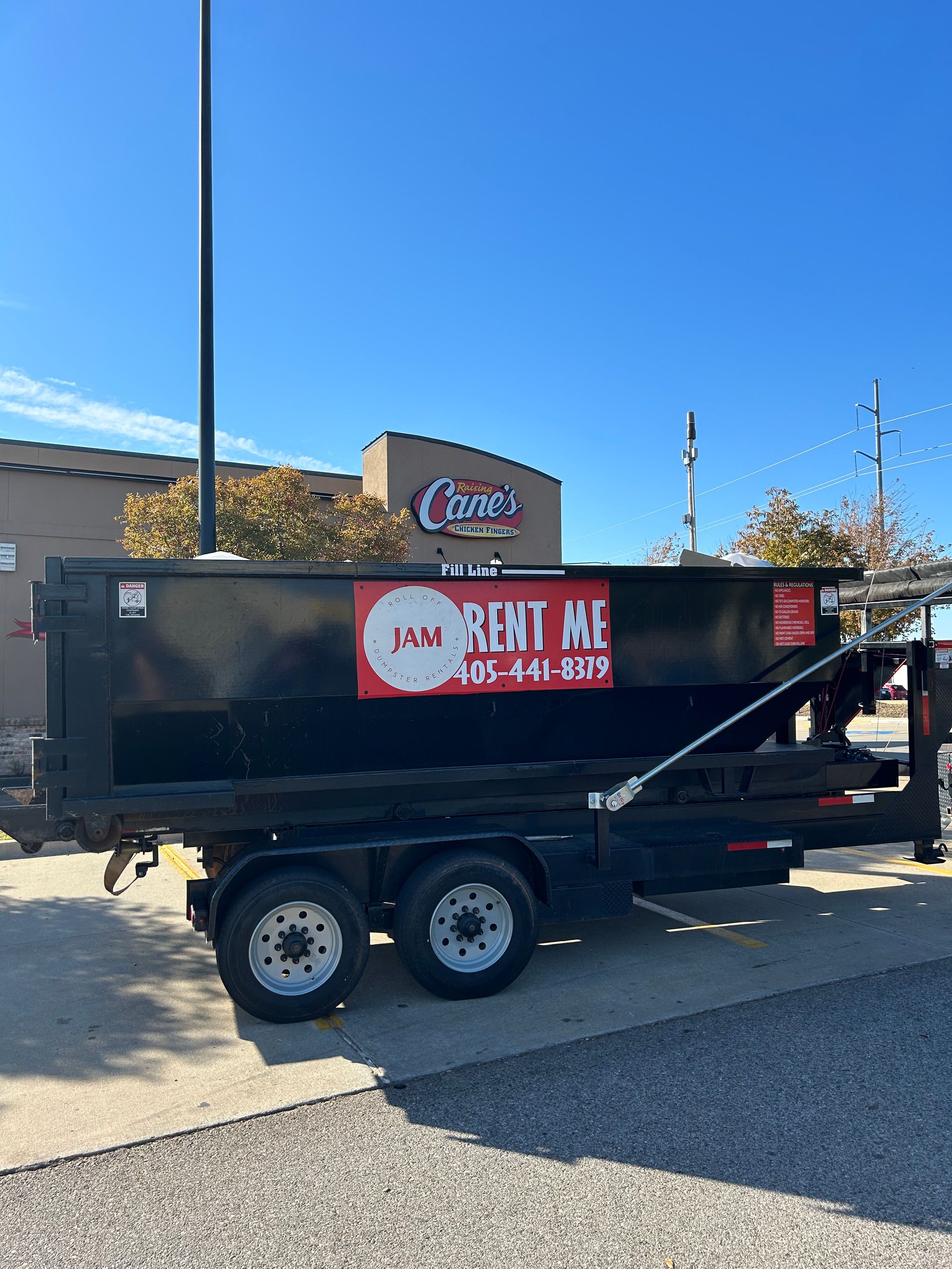 A dumpster is parked in a parking lot in front of a building.