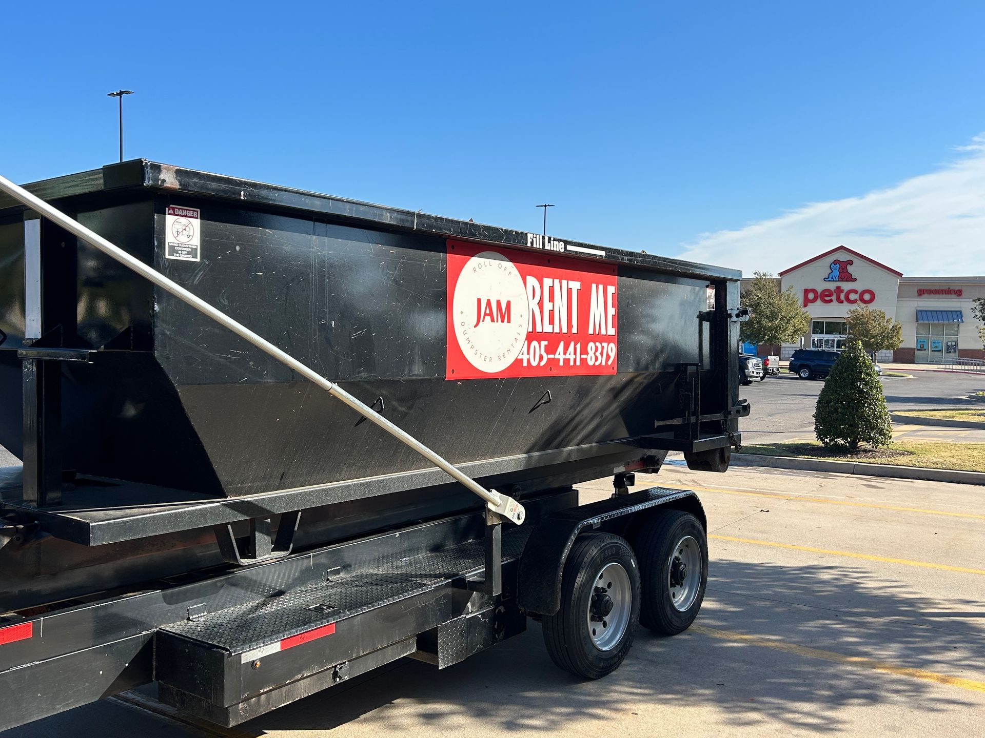 A dumpster is parked in front of a petco store