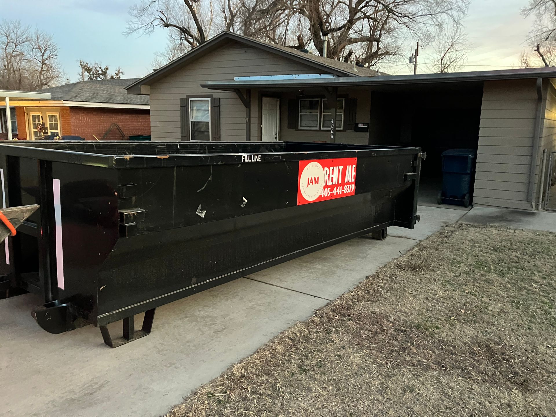 A dumpster is parked in front of a house.