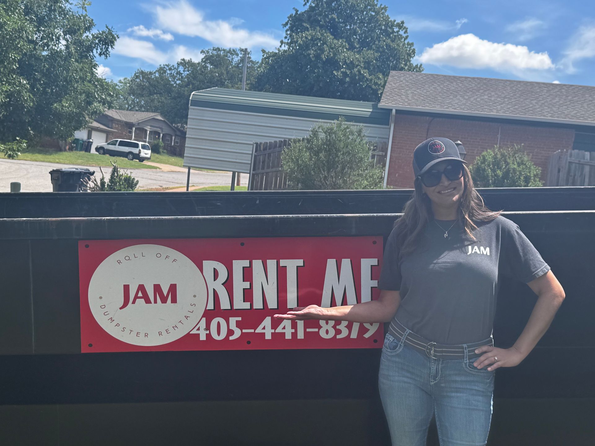 A woman is standing in front of a dumpster with a sign that says jam rent me.