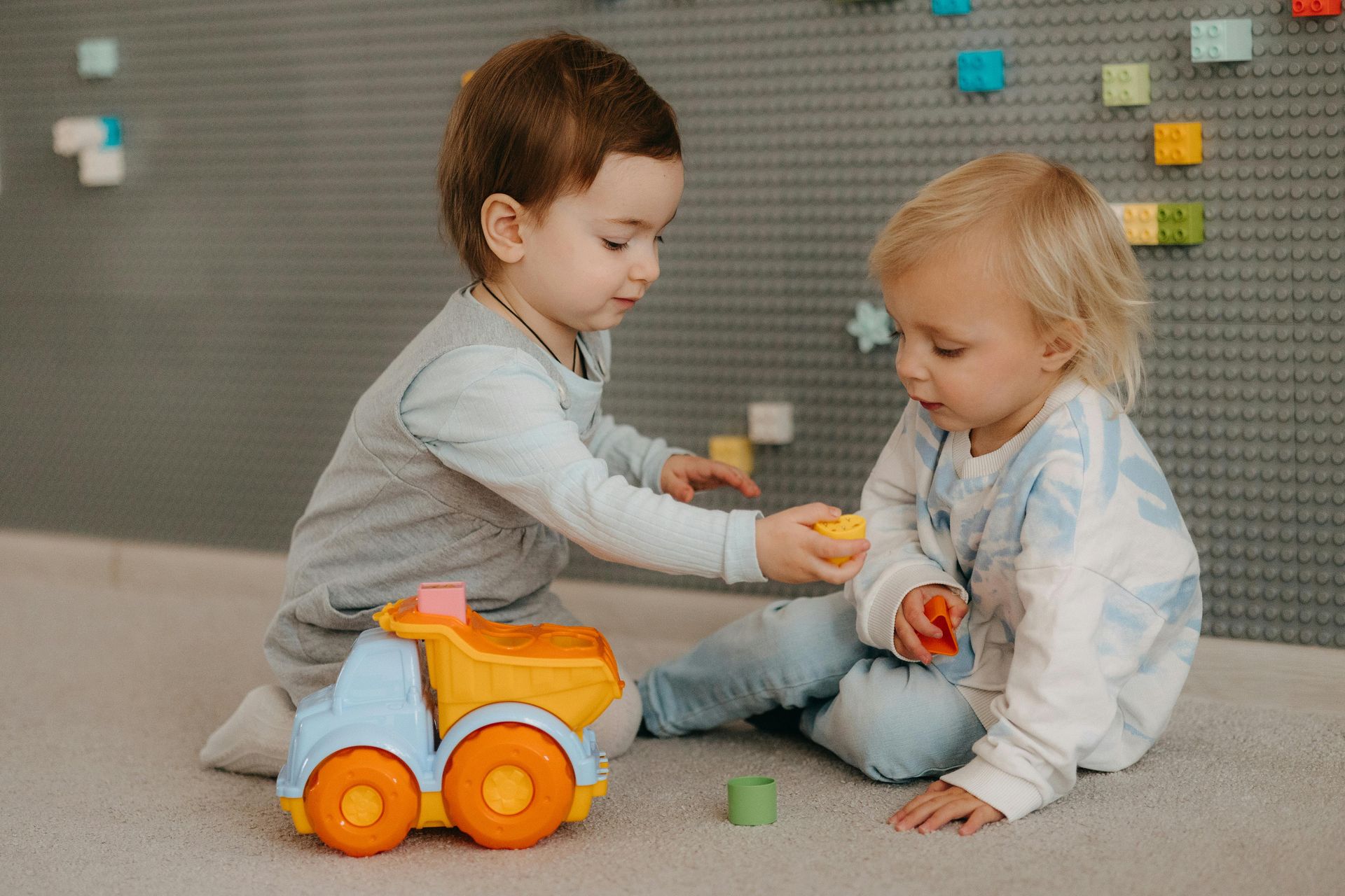 Due bambini stanno giocando con i giocattoli sul pavimento.