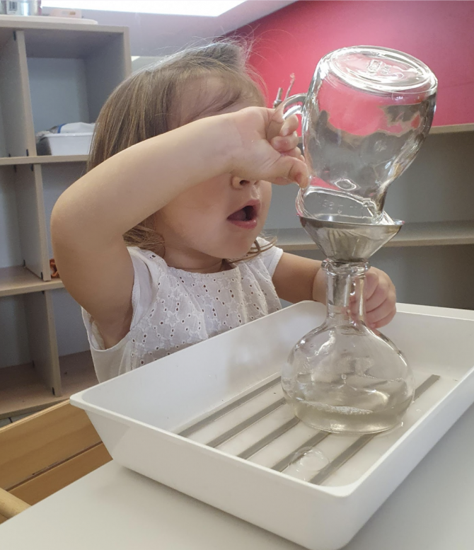 Una bambina sta versando acqua in una clessidra.
