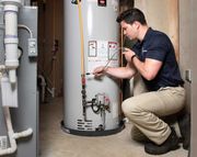 Technician inspecting a water heater in a basement utility room.