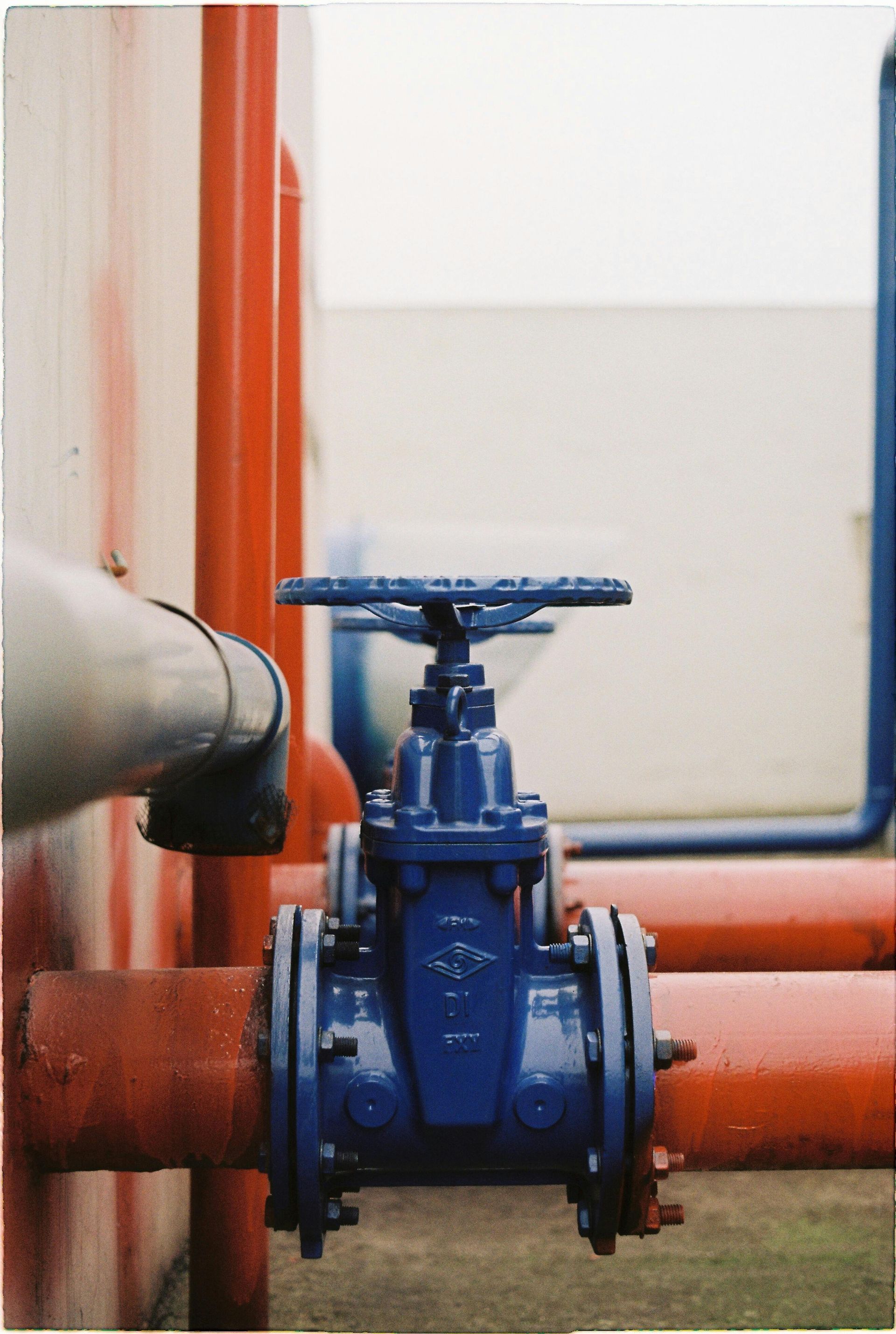 Blue industrial valve on red pipes in a utility room