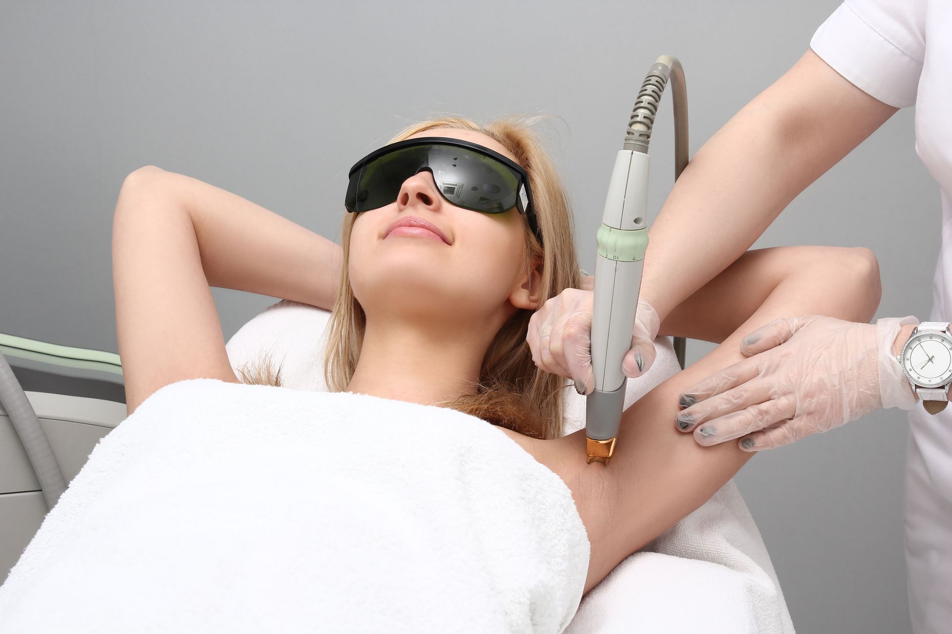 Woman receiving a facial treatment while wearing protective goggles in a spa chair
