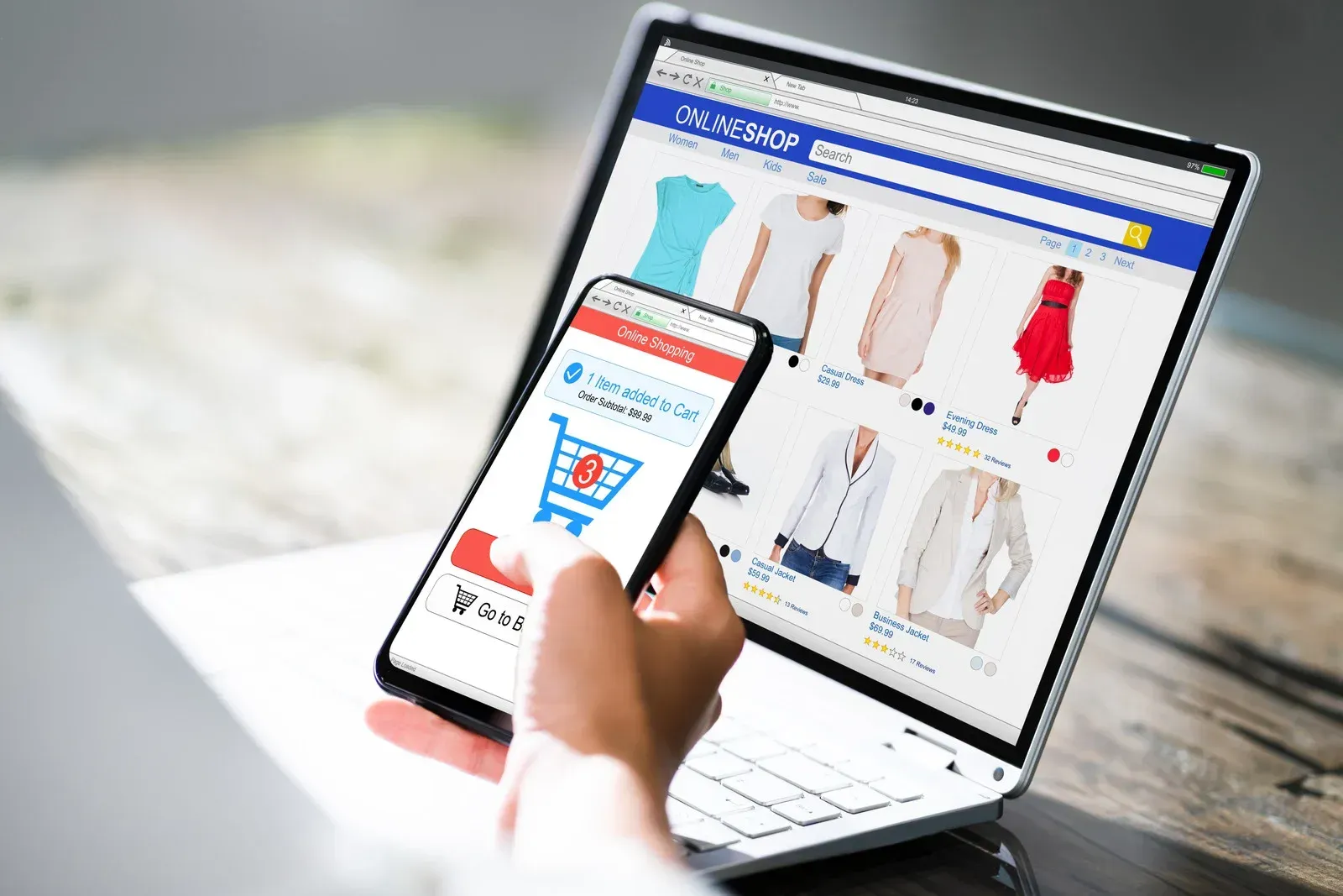 Person shopping online using laptop and phone, with clothing options displayed.