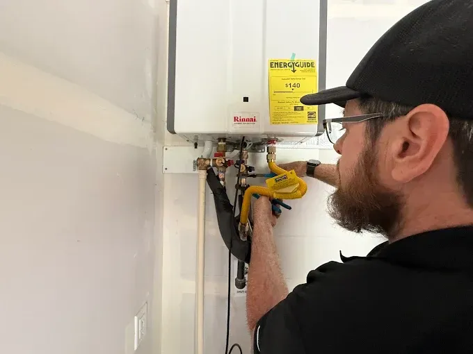 Technician inspecting a wall-mounted boiler with tools in a bright utility room