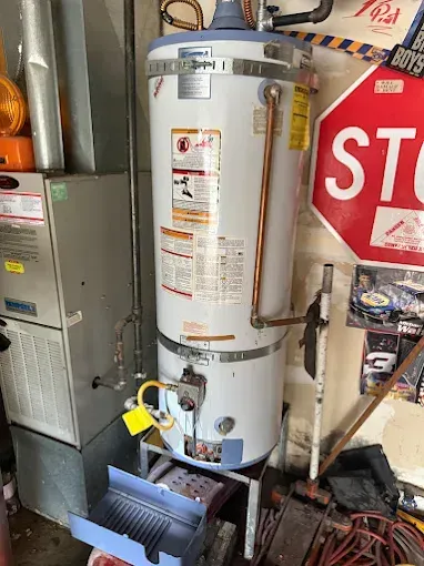 Utility room with a tall water heater, furnace, and stop sign in the background