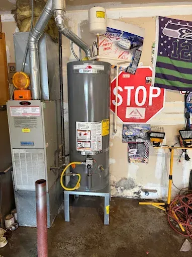 Water heater and furnace in a utility room beside a red STOP sign and pipes.