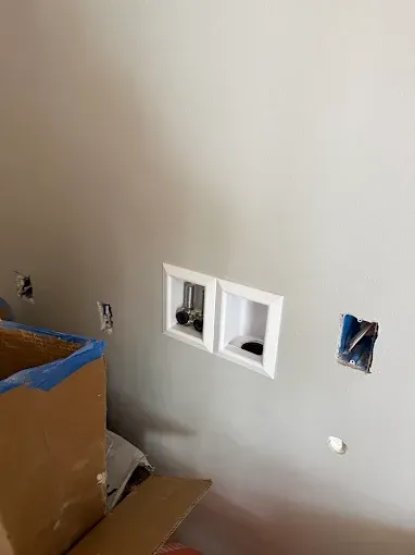 Unfinished wall with electrical outlets and open wall boxes beside a cardboard box during renovation