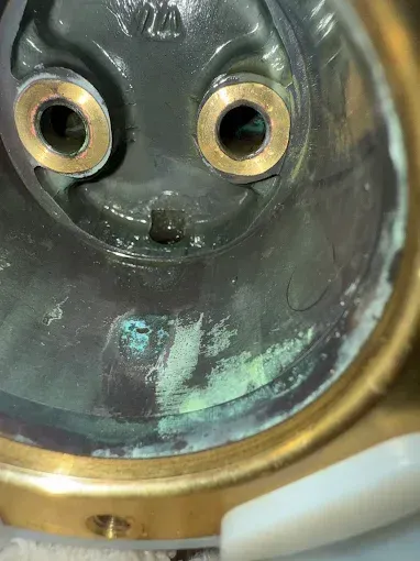 Close-up of a worn metal face-like interior with two circular openings and green corrosion stains