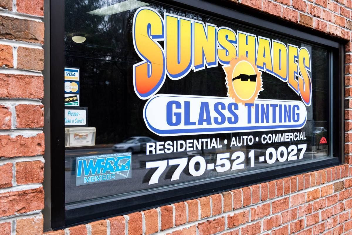 Sunshades Glass Tinting storefront sign on brick building. Includes logo, services, and phone number.