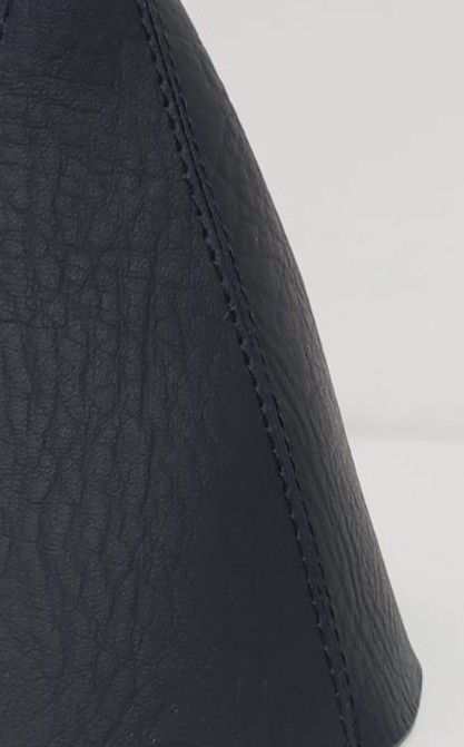 Estuche cónico de piel negra con costura cosida sobre fondo claro.