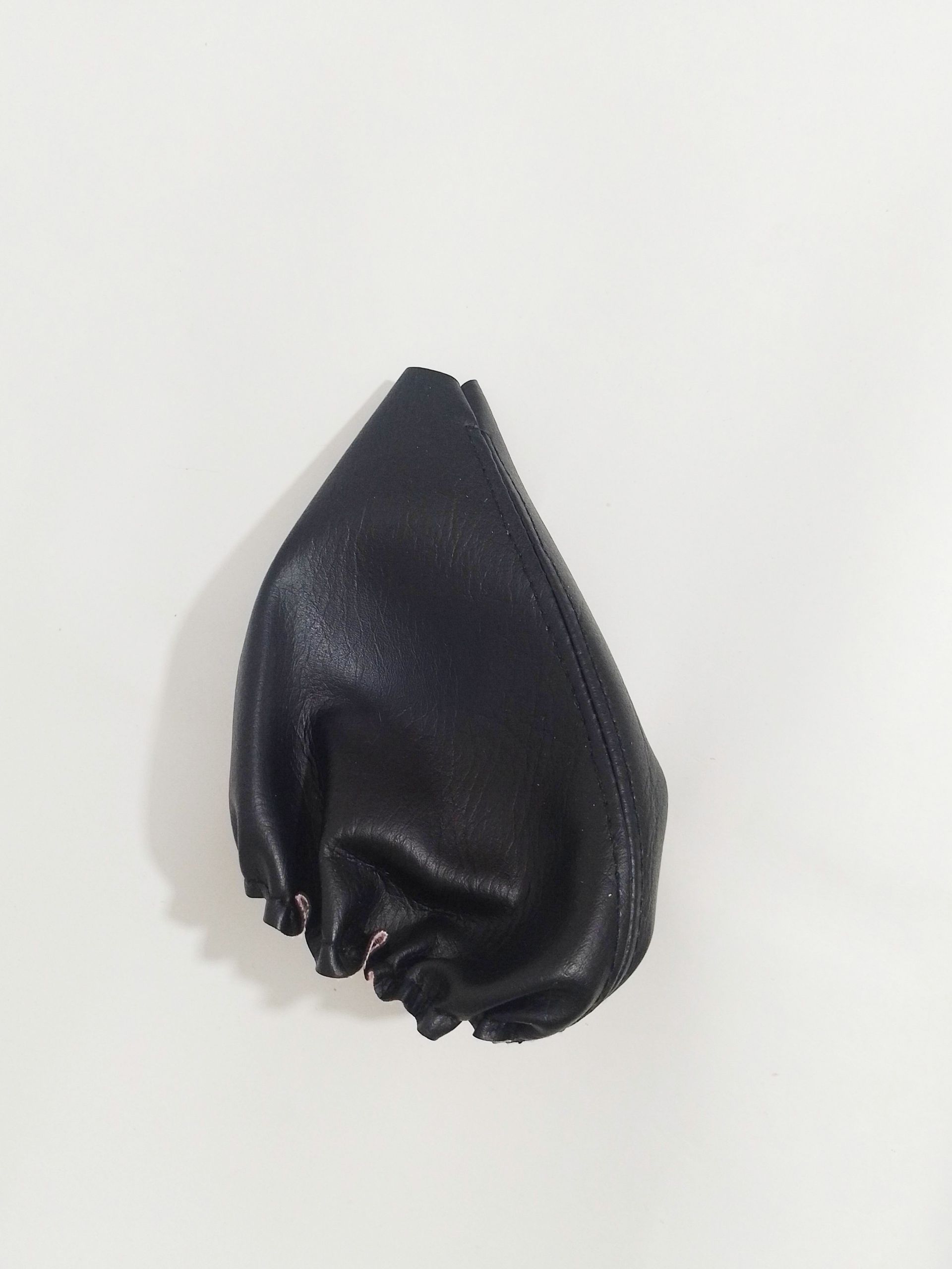 Bolsa de tela negra con cordón, colocada en posición vertical sobre un fondo liso y claro.